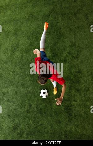 A female athlete in a green jersey dribbles a soccer ball on a white ...