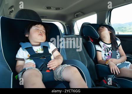 Sister and brother sleeping in car seat Stock Photo
