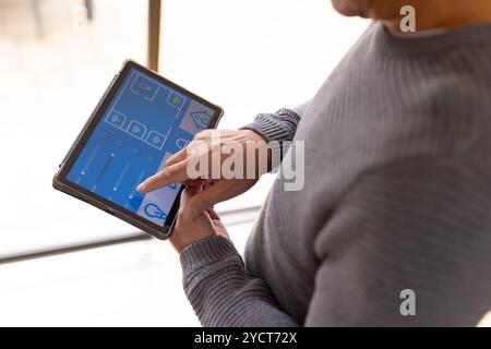 Asian senior man using tablet to control smart home devices, adjusting settings easily Stock Photo