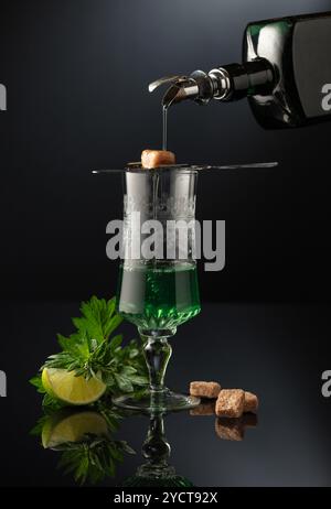 Absinthe is poured from an vintage bottle into a glass. Preparation of ...