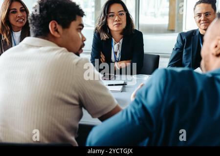 Diverse group of colleagues having an engaging discussion in a modern office setting. Team collaboration and brainstorming session. Stock Photo