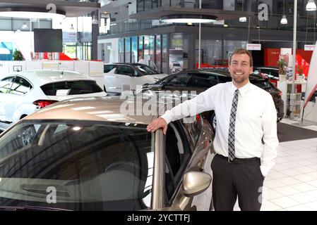 portrait successful businessman in a car dealership - sale of vehicles to customers Stock Photo