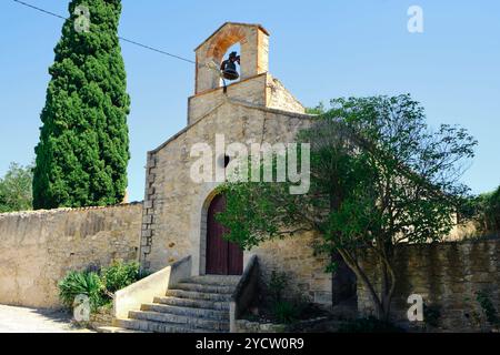 a view of St John the Baptist Church in Vallverd, in Catalonia, Spain, and the cemetery attached to it, with a tall cypress tree, characteristic trees Stock Photo