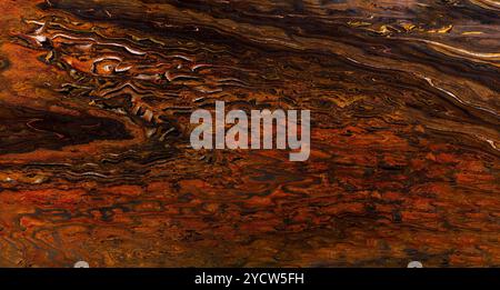 Natural granite stone texture featuring rich orange, brown, and black swirling patterns. Stock Photo