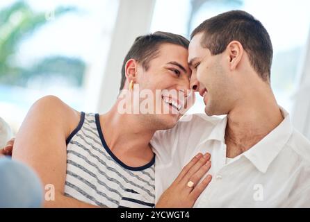 Laughing, gay and happy couple hug in home to relax for queer pride for homosexual, love or comfort. People, affection and men bonding with funny joke Stock Photo