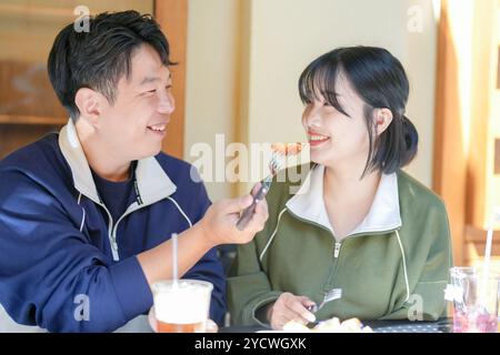 A couple, a Korean man in his 30s and a woman in her 20s, wear tracksuits and enjoy an afternoon at a nice Western-style cafe in Seoul, South Korea. Stock Photo