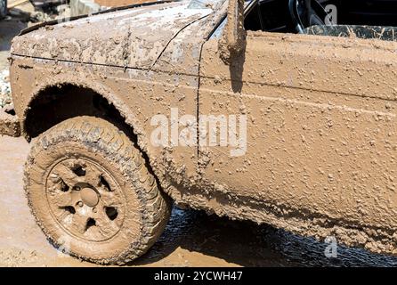 Off-road vehicle after driving in the rain on extremely dirty rural road Stock Photo