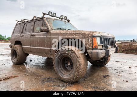Off-road vehicle after driving in the rain on extremely dirty rural road Stock Photo