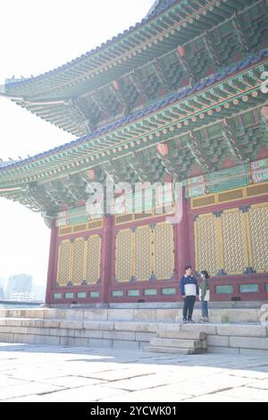 A sporty Korean couple, a man in his 30s and a woman in her 20s, wearing tracksuits, spends their time together happily at a historical building in Se Stock Photo