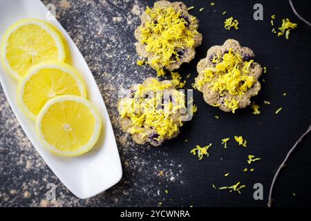 Lemon cupcakes on a black background and a lemon on a plate. Stock Photo