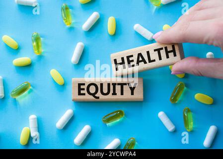 Health Equity symbol. Wooden blocks with words Health Equity. Beautiful blue background with pills. Doctor hand. Medicine and Health Equity concept. C Stock Photo