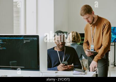 Young Specialists Checking Data Using Gadgets Stock Photo