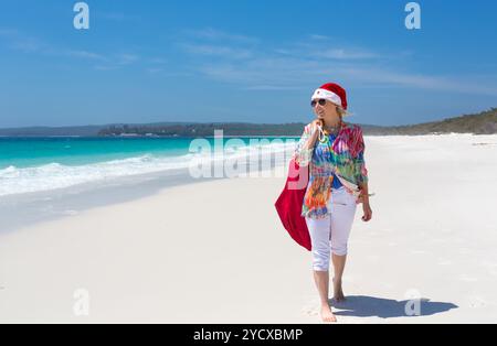 Christmas down on the beach summer sun female walking with santa hat Stock Photo