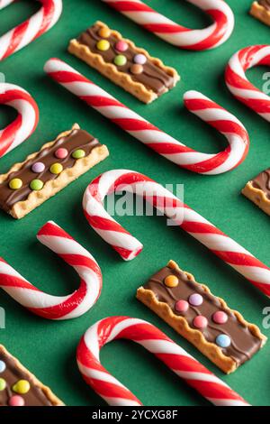 A festive display of Christmas confections including red and white candy canes and butter cookies topped with chocolate and colorful candies, set agai Stock Photo