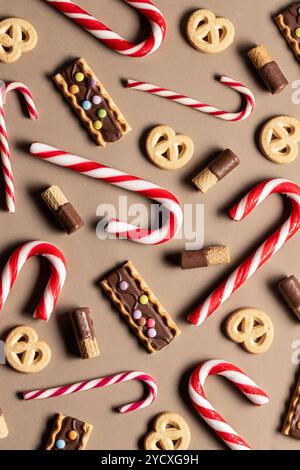 Top view of an arrangement of Christmas sweet treats including red and white candy canes, chocolate-covered biscuits with colorful toppings, and butte Stock Photo