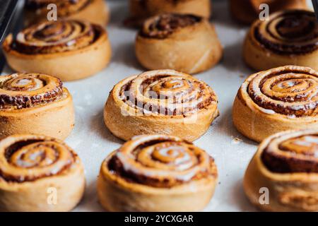 Close-up of warm, freshly baked cinnamon rolls covered with a smooth, sugar glaze, served on a baking sheet Stock Photo