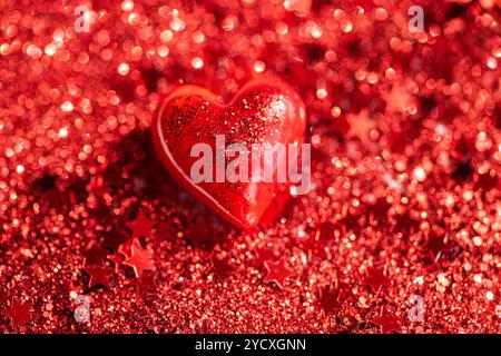 A vivid image presenting a heart-shaped object centered on a shimmering red glitter backdrop, perfect to evoke a romantic mood Stock Photo