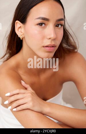 An elegant Latina model showcases flawless skin while posing subtly with a gentle expression Her natural makeup emphasizes her youthful glow and healt Stock Photo