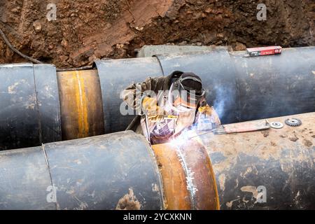 Worker with protective mask welding metal with sparks and smoke Stock Photo