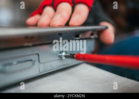 Technician carefully repairs a laptop motherboard in a workshop, showcasing expertise in electronics maintenance Stock Photo
