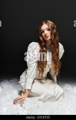 The stunning woman with flowing hair poses elegantly while surrounded by soft textures. Stock Photo
