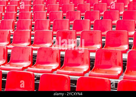 Rows empty bright red plastic seats in a stadium Stock Photo