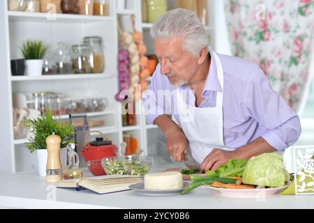 Elderly man in apron preparing healthy food at home Stock Photo