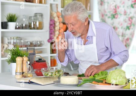 Elderly man in apron preparing healthy food at home Stock Photo
