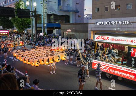 Akita, Japan - August 5, 2024: A traditional dancer carries a towering kanto, a bamboo pole adorned with hundreds of paper lanterns, during the Akita Stock Photo