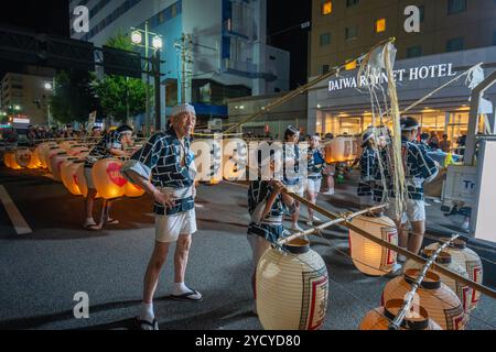 Akita, Japan - August 5, 2024: Young participants carry large Kanto lanterns through the streets of the city under the guidance of experienced elders. Stock Photo