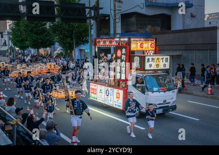 Akita, Japan - August 5, 2024: A traditional dancer carries a towering kanto, a bamboo pole adorned with hundreds of paper lanterns, during the Akita Stock Photo