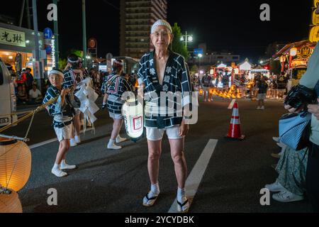 Akita, Japan - August 5, 2024: Young participants carry large Kanto lanterns through the streets of the city under the guidance of experienced elders. Stock Photo