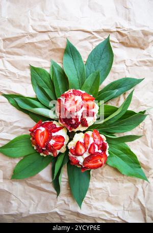 Beautiful and bright cupcakes with strawberries lie on green leaves Stock Photo