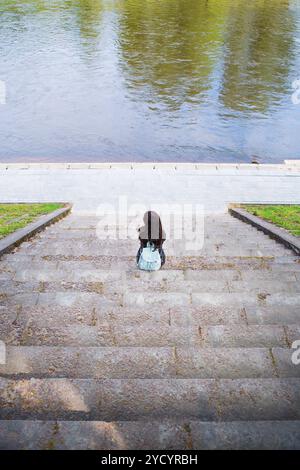Beautiful girl sits and looks at the river Vilnius Stock Photo - Alamy