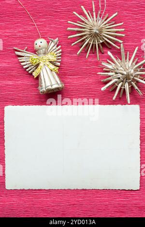 blank vintage postcard on red paper background with snowflakes and toy angel figurine Stock Photo