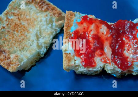 A buttered toast with strawberry jam for breakfast. Stock Photo