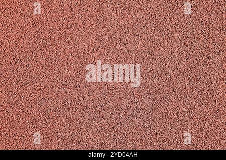 Red rubber floor, texture, background. Relief surface. Faded, old, granular rubber coating and surface with blurry chaotic pattern. Embossed patterns Stock Photo