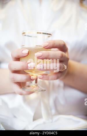 Bride's hand with wedding ring holding a glass of champagne and bubbles Stock Photo