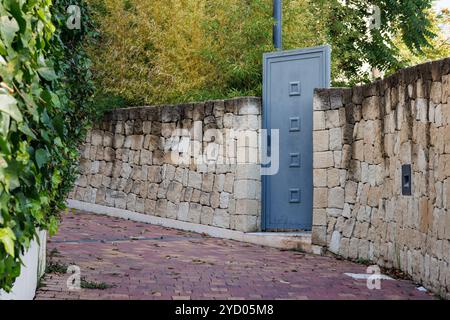 Blue metal gate in stone wall in a narrow street, Spain Stock Photo