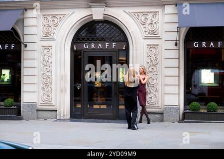 Young woman photographer photographing older woman female model outside GRAFF jewellery store on New Bond Street in London W1 England UK KATHY DEWITT Stock Photo