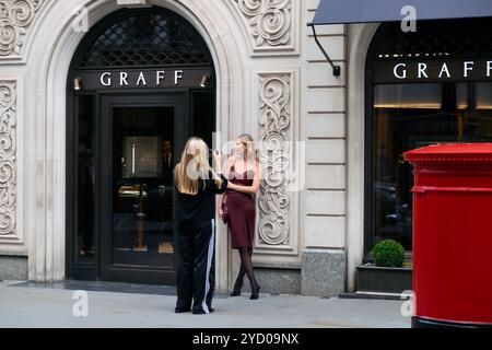 Young woman photographer photographing older woman female model outside GRAFF jewellery store on New Bond Street in London W1 England UK KATHY DEWITT Stock Photo