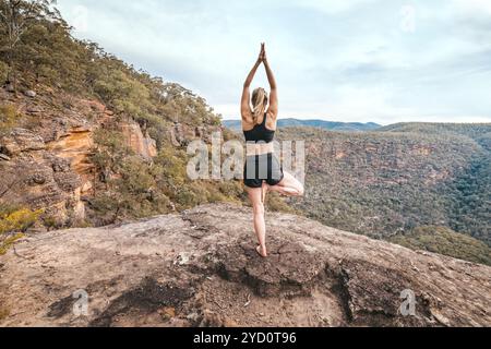 Female strength yoga balance asana mountain cliff ledge Stock Photo