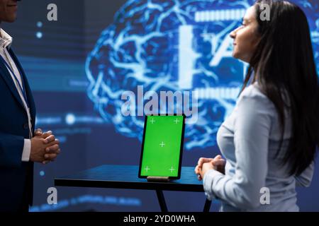 Teamworking colleagues in startup doing advancements in AI field using chroma key tablet. Mockup device used by programming team coworkers working in high tech lab featuring artificial intelligence Stock Photo