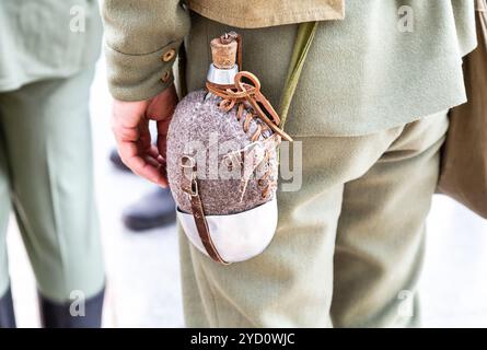 Vintage military flask hangs on a belt from a soldier Stock Photo