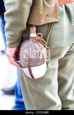 Vintage military flask hangs on a belt from a soldier Stock Photo