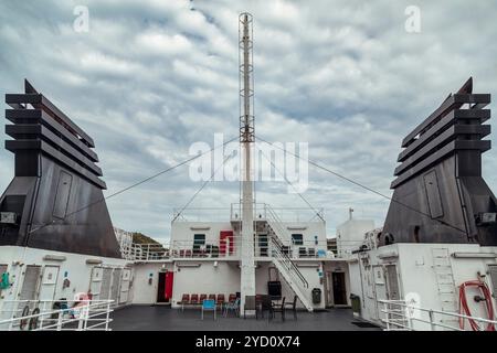 A passenger ship's deck showcases its naval architecture, set against the breathtaking backdrop of Lofoten Islands, with clouds casting shadows over t Stock Photo