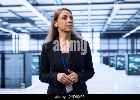 IT specialist walking in data center with advanced technology, ensuring cybersecurity and efficient network management. Engineer in server hub maintaining and optimizing data center infrastructure Stock Photo