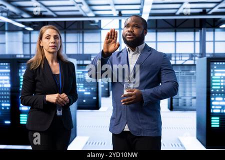 Coworkers in data center checking rigs and hardware, doing checkup with AR tech. IT staff members planning and executing server room migrations and upgrades using augmented reality Stock Photo