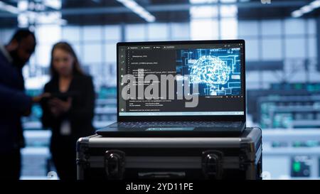 Focus on laptop in data center with artificial intelligence brain used by engineers in blurry background. Close up of device displaying AI deep learning software in server farm, camera A Stock Photo