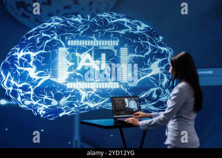 Computer scientist in startup doing advancements in AI field. Woman working on laptop in cutting edge workspace featuring artificial intelligence and neural network systems Stock Photo